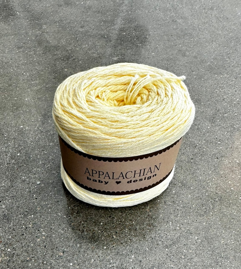 May include: A ball of pale yellow yarn with a brown label that reads "Appalachian Baby &hearts; Design".
