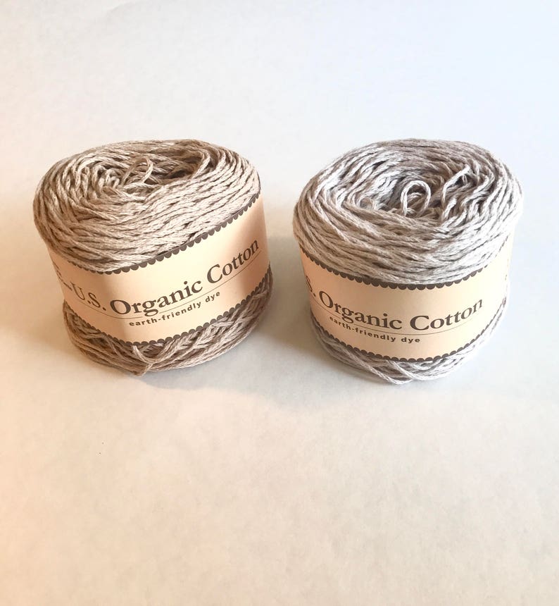 May include: Two spools of beige organic cotton yarn with brown labels that read "U.S. Organic Cotton earth-friendly dye".