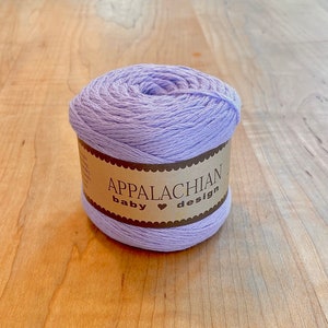 May include: A skein of lavender colored yarn with a brown label that reads "Appalachian baby &hearts; design".