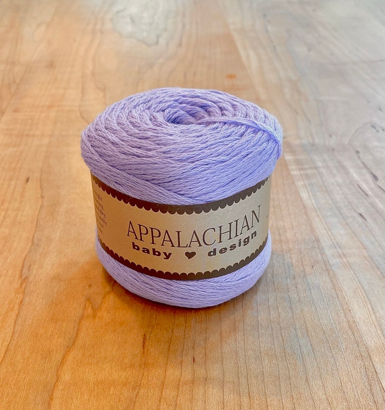 May include: A skein of lavender colored yarn with a brown label that reads "Appalachian baby &hearts; design".