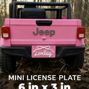 May include: A pink toy Jeep with black accents and a license plate that reads "Loxley." The license plate is 6 inches by 3 inches. The Jeep has a black roll bar and a black seat. The word "Jeep" is displayed on the back of the vehicle.