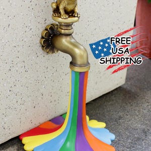 May include: A whimsical garden faucet sculpture featuring a golden frog perched atop. The faucet flows with a vibrant rainbow of colors, creating a decorative and eye-catching piece for outdoor spaces.