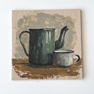 Può includere: Un dipinto a olio su tela quadrata raffigurante una caffettiera in smalto verde scuro e una tazza in smalto bianco abbinata. Gli oggetti sono realizzati con pennellate spesse e visibili su uno sfondo beige strutturato e una superficie marrone.