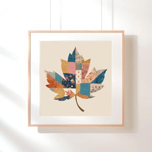 Pode incluir: Uma impressão artística emoldurada com um design de folha de bordo em patchwork colorido. A folha é composta por vários pedaços de tecido estampado em tons de azul, laranja, rosa e dourado. A obra de arte está sobre um fundo creme.