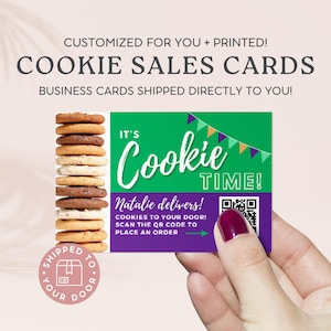 May include: A green and purple business card with the text "It's Cookie Time!" and a QR code. The text "Natalie delivers! Cookies to your door! Scan the QR code to place an order" is also on the card. The card is being held by a hand.