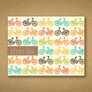May include: A cream-colored card with a repeating pattern of colorful bicycles. The bicycles are in various colors, including red, orange, yellow, green, blue, and black. The word "thanks" is in a brown rectangle.