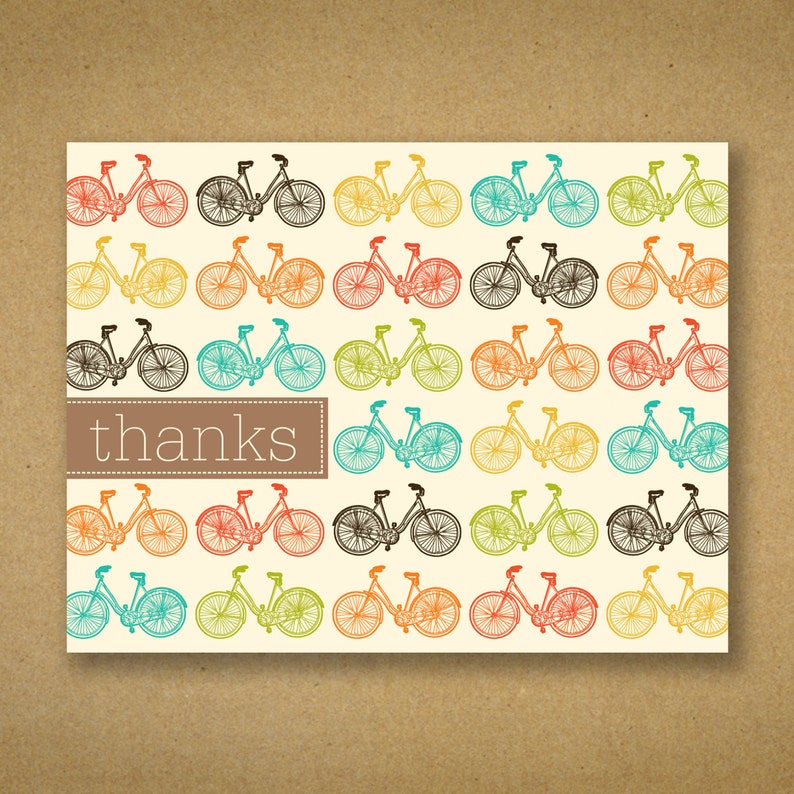 May include: A cream-colored card with a repeating pattern of colorful bicycles. The bicycles are in various colors, including red, orange, yellow, green, blue, and black. The word "thanks" is in a brown rectangle.