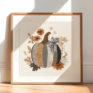 May include: Framed artwork of a patchwork pumpkin with a brown stem and a gingham bow. The pumpkin is surrounded by autumn-toned flowers and foliage. The artwork is set against a cream background with a subtle grid pattern.
