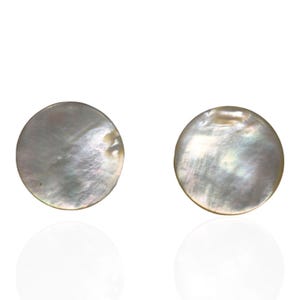 May include: Two circular, flat buttons crafted from iridescent mother-of-pearl shell. Each button features a smooth, polished surface with natural swirling patterns in shades of white, cream, and soft gray, displaying a subtle pearlescent sheen.
