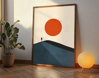 Może przedstawiać: Oprawiony wydruk artystyczny z minimalistycznym krajobrazem. Grafika przedstawia duże pomarańczowe słońce, sylwetkę na niebieskim wzgórzu i białe niebo. Rama jest z ciemnego drewna. Wydruk opiera się o ścianę.