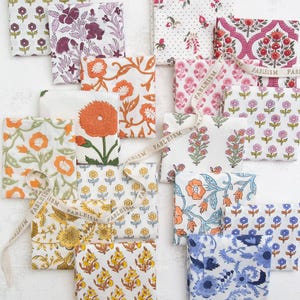 May include: A collection of patterned fabric squares in various floral designs. The fabrics feature colors like orange, purple, pink, yellow, and blue. A ribbon with the word "FABLEISM" is woven throughout the arrangement.