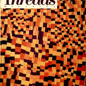 May include: The cover of Threads magazine, Oct/Nov 1988, features a patchwork quilt design. The quilt is composed of various squares in shades of orange, yellow, black, and purple. The magazine title is in large, bold letters.
