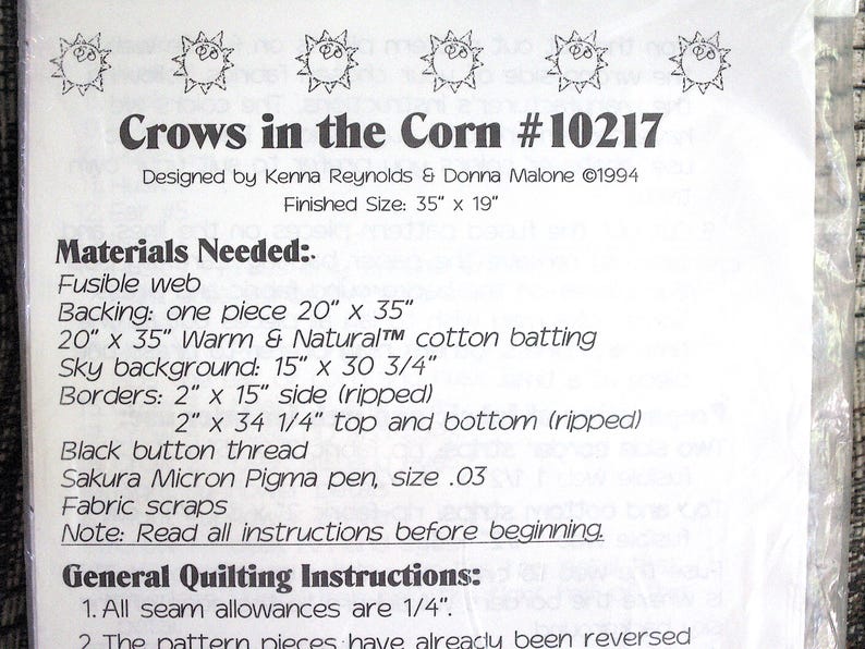 K&ouml;nnte beinhalten: Ein wei&szlig;es Papierschnittmuster mit dem Titel Crows in the Corn #10217, entworfen von Kenna Reynolds und Donna Malone im Jahr 1994. Das Dokument listet ben&ouml;tigte Materialien wie Vlieseline, Baumwollvlies und Stoffreste auf, Endgr&ouml;&szlig;e 89 x 48 cm.