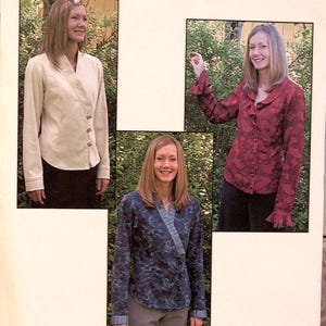 May include: A sewing pattern envelope titled Purrfection Artistic Wearables 1039 Modern Poet. It displays three variations of a long-sleeved top: a solid cream wrap-style jacket, a dark red patterned shirt with ruffled cuffs, and a blue patterned wrap top.