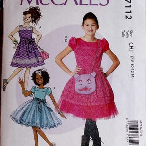 May include: McCall's M7112 sewing pattern for girls' dresses. The pattern features illustrations of three different dress designs, including a pink dress with a cat-shaped purse. The pattern size range is CHJ (7-8-10-12-14).