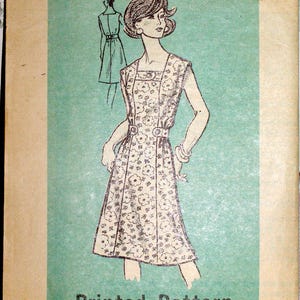 May include: A vintage sewing pattern envelope featuring a line drawing of a floral print dress with a square neckline and a belted waist. The text reads Printed Pattern, 9477, and SIZE 20 1/2. The illustration is set against a light green background.
