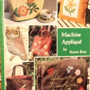 May include: A book cover with the title "Machine Appliqué" by Karen Bray. The cover features various examples of machine appliqué projects, including a tea cozy, a pillow, a tote bag, and a sewing machine cover.