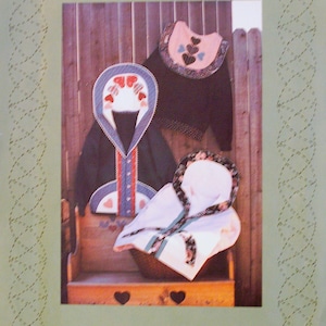 May include: A vintage sewing pattern for a "Sweatjacket II" from "A Quilter's Wardrobe". The pattern features a hooded jacket with a heart-shaped design and a matching collar.