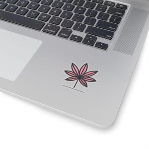 May include: A pink and black leaf design sticker on a silver laptop.
