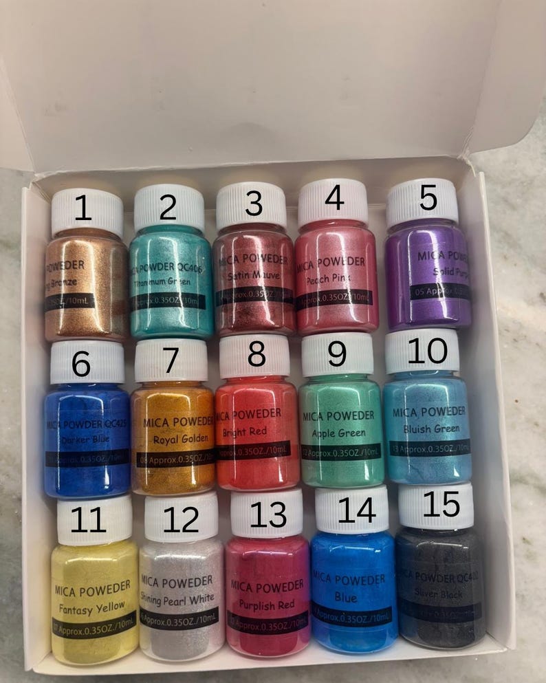 May include: A collection of 15 small jars of mica powder in various colors, including bronze, teal, mauve, peach, purple, blue, gold, red, green, and black. Each jar is labeled with a color name and volume of 0.35 oz / 10ml.
