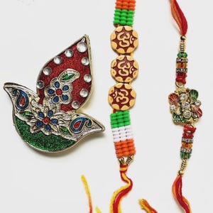 May include: A decorative dove-shaped ornament with red, green, and blue accents, and a pair of colorful bracelets. The bracelets feature intricate beadwork and charms in various colors, including orange, green, and gold. The dove has clear crystal accents.