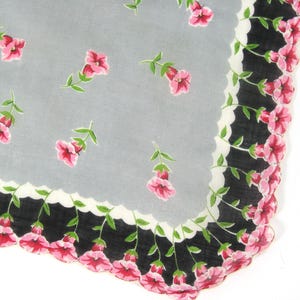 Pode incluir: Um len&ccedil;o cinza com uma borda preta e branca e flores cor-de-rosa. A borda tem uma borda festonada.