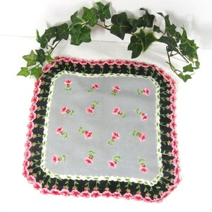Pode incluir: Um len&ccedil;o vintage com um delicado padr&atilde;o floral. O len&ccedil;o apresenta um fundo cinza com flores cor-de-rosa e caules verdes. A borda &eacute; preta com uma guarni&ccedil;&atilde;o branca e bordas festoneadas cor-de-rosa.
