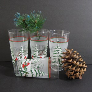 May include: Set of four frosted glass tumblers with a winter scene design. The glasses feature a red and green band around the top and a snowy landscape with trees and houses.