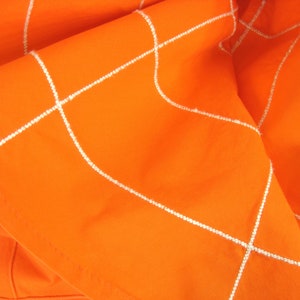 May include: Orange fabric with white stitching in a grid pattern.