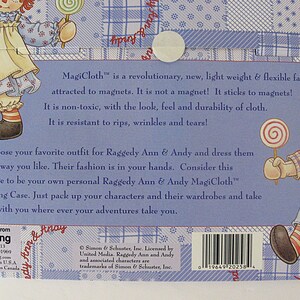 May include: Back of a Raggedy Ann & Andy MagiCloth carrying case. The blue background features illustrations of the characters and text describing the fabric's features. Includes a barcode and the text "More Fun From Schylling".