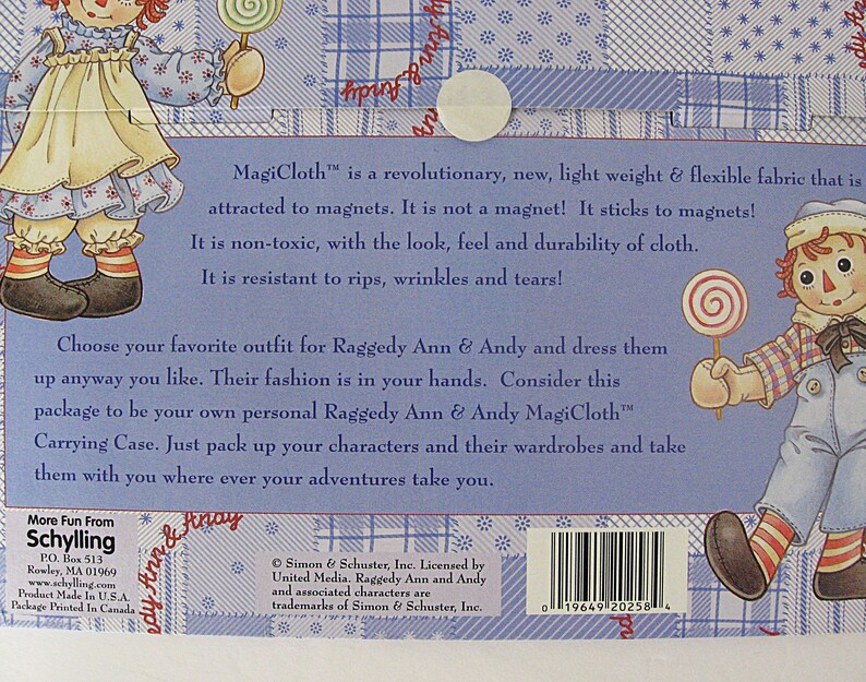 May include: Back of a Raggedy Ann & Andy MagiCloth carrying case. The blue background features illustrations of the characters and text describing the fabric's features. Includes a barcode and the text "More Fun From Schylling".