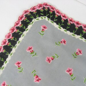 Pode incluir: Um len&ccedil;o cinza com uma borda festonada preta e branca. A borda &eacute; decorada com flores cor-de-rosa. O centro do len&ccedil;o &eacute; cinza claro com um padr&atilde;o de flores cor-de-rosa.