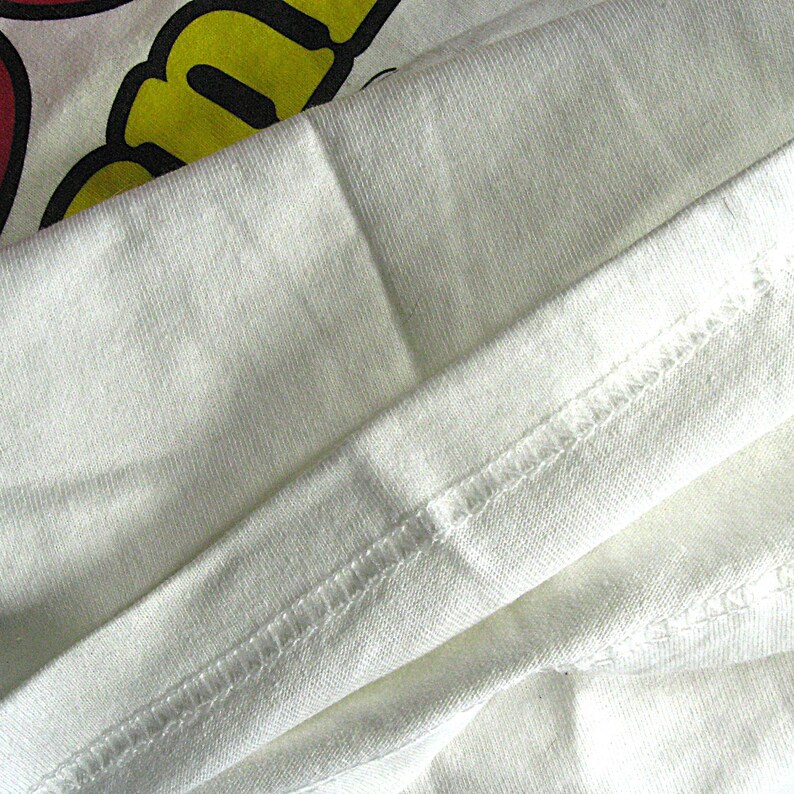 K&ouml;nnte beinhalten: Nahaufnahme eines wei&szlig;en T-Shirts mit einem umgeschlagenen Saum. Der Stoff ist weich und die N&auml;hte sind sauber.