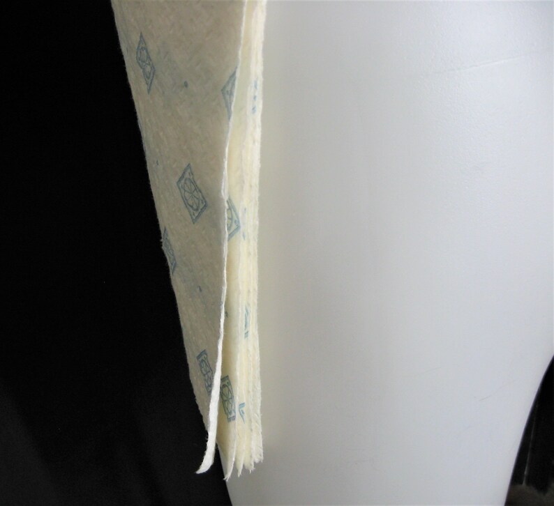May include: A stack of off-white fabric with a blue geometric pattern. The fabric is folded and the edges are frayed.