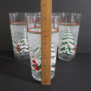 May include: Set of six frosted glass tumblers with a winter scene design. The glasses feature a white frosted background with green trees, red houses, and white snow. The glasses have a red and green stripe around the top.