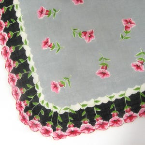 Pode incluir: Um len&ccedil;o vintage com fundo cinza e uma borda festonada preta e branca. O len&ccedil;o &eacute; decorado com flores cor-de-rosa.