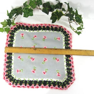 Pode incluir: Um len&ccedil;o vintage com um delicado padr&atilde;o floral. O len&ccedil;o &eacute; branco com uma borda preta e rosa. Tem aproximadamente 28 cm de lado.
