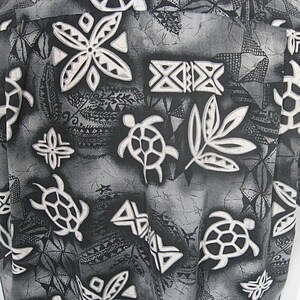 May include: A button-down shirt featuring a monochromatic black, gray, and white print. The pattern consists of stylized sea turtles, geometric shapes, and leaf-like motifs set against a textured, mottled background with a batik-style aesthetic.