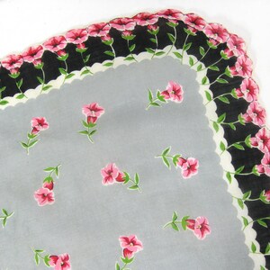 Pode incluir: Um len&ccedil;o vintage com fundo cinza e uma borda branca festonada. O len&ccedil;o &eacute; decorado com um padr&atilde;o repetido de flores cor-de-rosa com caules verdes.