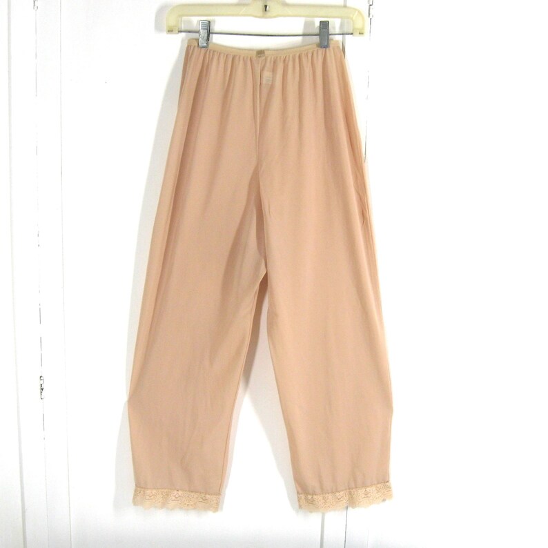 May include: A pair of beige nylon slip-on pants with lace trim at the bottom.