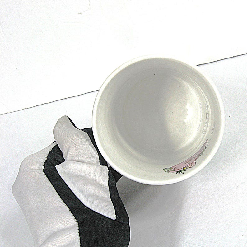 May include: White ceramic mug with a floral design. The mug is empty and the inside is visible.