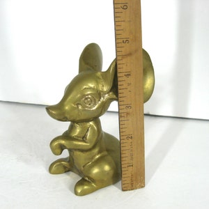 May include: A solid brass figurine of a mouse with large ears. The mouse is sitting upright with its paws in front of it. The figurine is about 4 inches tall.