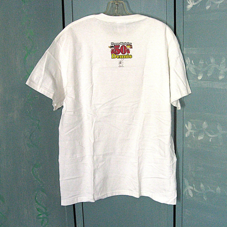 K&ouml;nnte beinhalten: Wei&szlig;es T-Shirt mit einer Grafik von Comicfiguren, die einen 50. Geburtstag feiern, mit dem Text "Happy Birthday 50 Dennis".