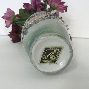 Pode incluir: Um pequeno vaso de cer&acirc;mica vintage com um esmalte verde claro e azul. O vaso tem uma borda branca e uma guarni&ccedil;&atilde;o decorativa prateada. Um adesivo dourado na parte inferior diz "Imports EFCCO San Francisco California."