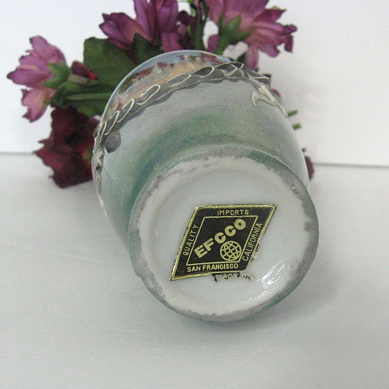 Pode incluir: Um pequeno vaso de cer&acirc;mica vintage com um esmalte verde claro e azul. O vaso tem uma borda branca e uma guarni&ccedil;&atilde;o decorativa prateada. Um adesivo dourado na parte inferior diz "Imports EFCCO San Francisco California."