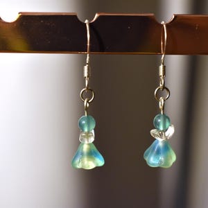 May include: A pair of dangle earrings with a blue and green glass bead and a silver hook.