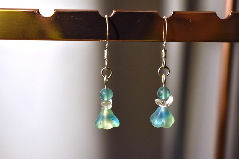 May include: A pair of dangle earrings with a blue and green glass bead and a silver hook.