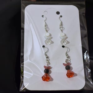 May include: A pair of earrings with white and clear beads and a pair of earrings with red and black beads.
