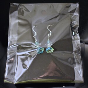 May include: A pair of silver dangle earrings with blue and green glass flower charms.