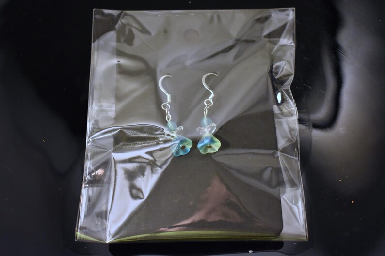 May include: A pair of silver dangle earrings with blue and green glass flower charms.
